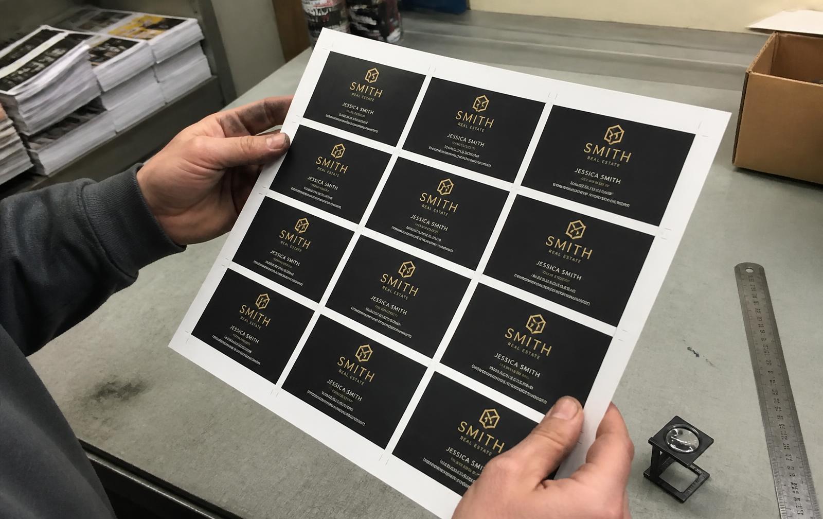 Printer holding a freshly printed sheet of business cards over the work table