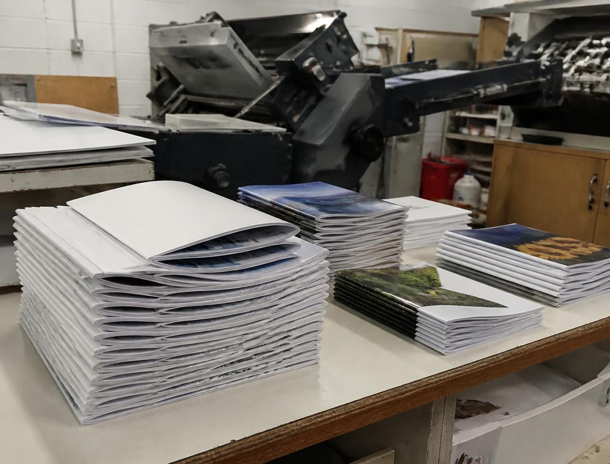 Stacks of folded booklets on the bindery table beside the folding machine