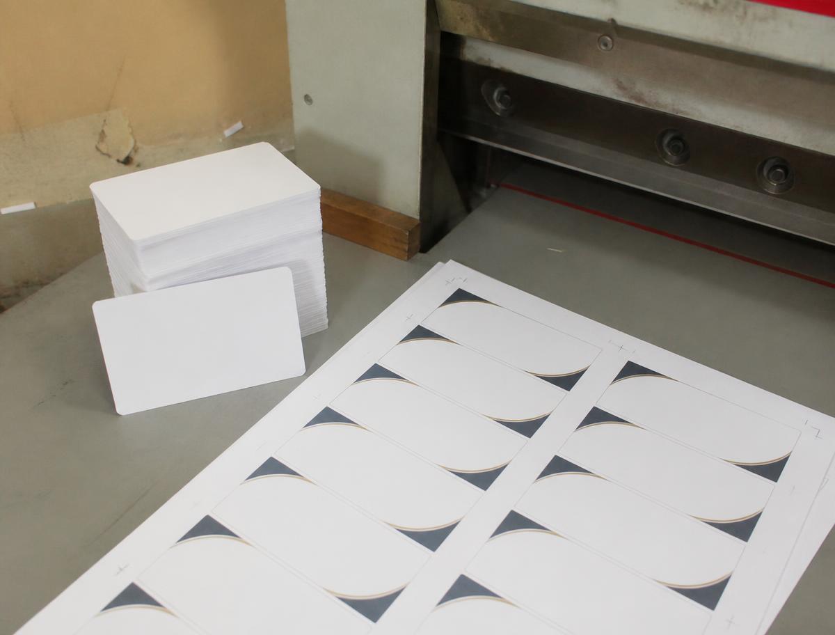Stack of cut business cards beside a printed card sheet at the cutter